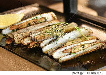 The shells knives, parsley and half a lemon on black plate The shells knives, parsley and half a lemon on black plate 104880148