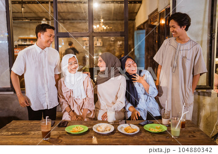 a group of Asian Muslim friends joking while gathering for iftar 104880342