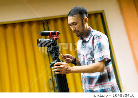 a handsome cameraman preparing his shooting equipment a handsome cameraman preparing his shooting equipment 104880410