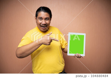 old asian man holding tablet and showing it to camera old asian man holding tablet and showing it to camera 104880484