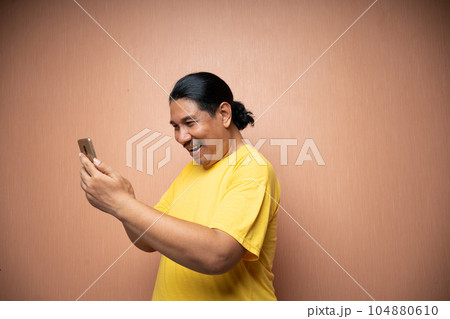old asian man holding handphone and using it to communicate 104880610