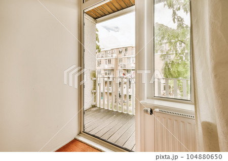 an empty room with wooden floors and white walls, looking out onto the street from one of the two windows an empty room with wooden floors and white walls, looking out onto the street from one of the two windows 104880650