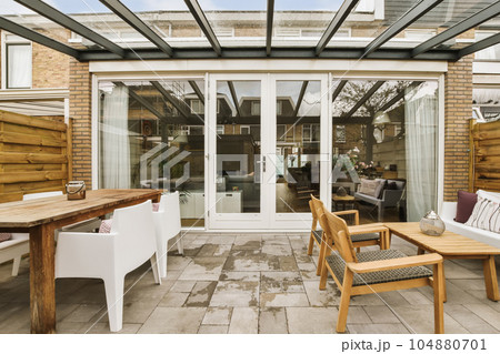 a patio with chairs, tables and an umbrella over the door that leads to a covered area for outdoor dining 104880701