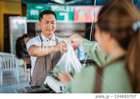 male seller putting the plastic bag on the scale male seller putting the plastic bag on the scale 104880707