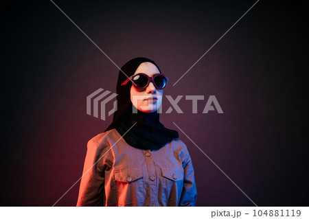 muslim woman wearing black hijab long dress and sunglasses posing sideways 104881119