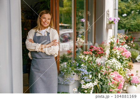 Smiling woman florist small business owner standing with crossed arms near own floral store Smiling woman florist small business owner standing with crossed arms near own floral store 104881169