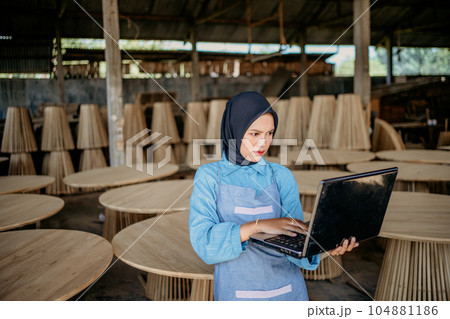 Veiled woman is using laptop computer at furniture craft shop 104881186