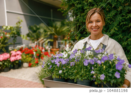 Smiling woman florist business owner standing with houseplants on background of floral store Smiling woman florist business owner standing with houseplants on background of floral store 104881198