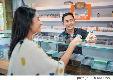 asian male shopkeeper showing the vape mod to the female customer asian male shopkeeper showing the vape mod to the female customer 104881199