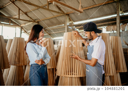 Asian male shop assistant serving customers while selecting wood products Asian male shop assistant serving customers while selecting wood products 104881201