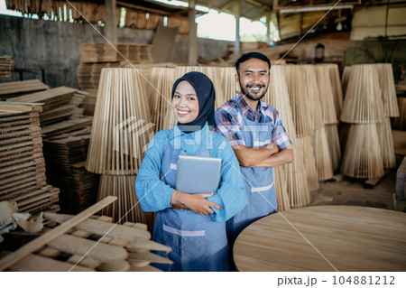 two smiling Asian entrepreneurs wearing aprons stand together with crossed hands two smiling Asian entrepreneurs wearing aprons stand together with crossed hands 104881212