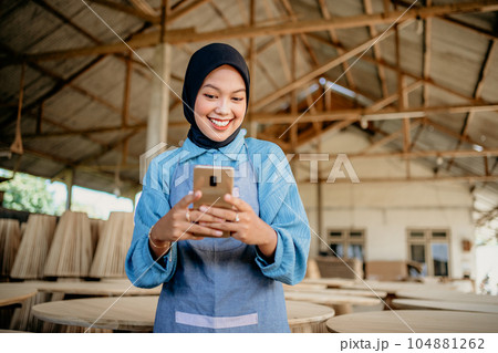 Muslim female entrepreneur uses a smartphone to send messages Muslim female entrepreneur uses a smartphone to send messages 104881262