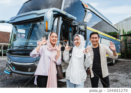 three young traveler smile showing thumb in front of the bus 104881270