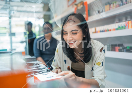 female seller smiling while picking the vape mod 104881302