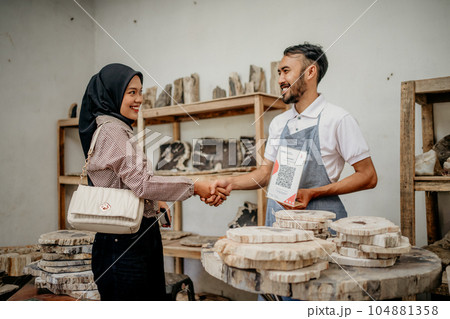 Veiled woman shakes hands during a transaction to buy stone handicrafts Veiled woman shakes hands during a transaction to buy stone handicrafts 104881358