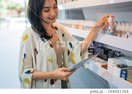 beautiful shopkeeper looking at the digital tablet while checking the liquid stock 104881368