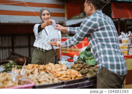 A beautiful girl wearing a headscarf selling a food stall on the side of the road gives takjil food A beautiful girl wearing a headscarf selling a food stall on the side of the road gives takjil food 104881393