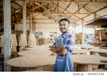 Asian entrepreneur man holding tablet with craft shop in the background 104881448