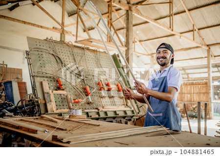 male carpenter smiles at camera while holding wood material male carpenter smiles at camera while holding wood material 104881465
