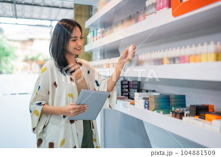 female shopkeeper smiling while checking the liquid stock at the vape store female shopkeeper smiling while checking the liquid stock at the vape store 104881509