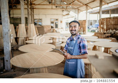 Asian businessman using tablet with wood craft shop in the background 104881554