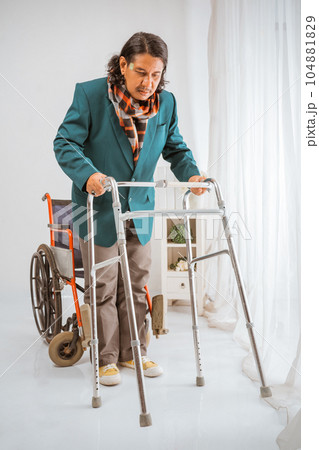 elderly man standing and trying to walk with walker frame 104881829