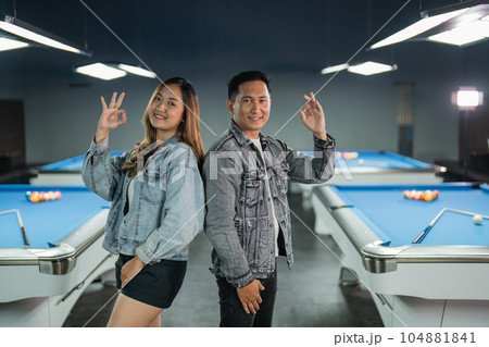 couple of billiard players standing back to back with oke hand gesture couple of billiard players standing back to back with oke hand gesture 104881841