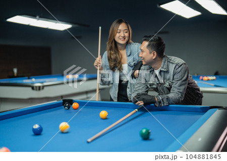 asian woman holding the cue stick while standing 104881845