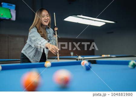 female billiard player pointing on the billiard balls while playing billiard 104881980
