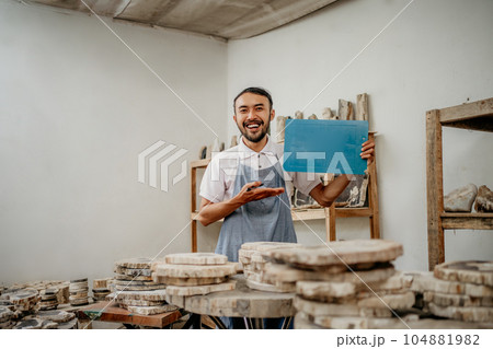 smiling male entrepreneur wearing apron with hands presenting something smiling male entrepreneur wearing apron with hands presenting something 104881982