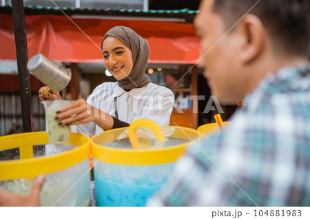 a pretty girl in a veil sells es campur using a scoop to get coconut milk a pretty girl in a veil sells es campur using a scoop to get coconut milk 104881983