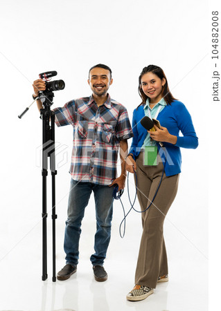 a beautiful reporter and the cameraman standing together with their equipment 104882008