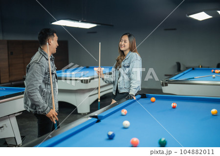 couple pool player chatting while standing beside the pool couple pool player chatting while standing beside the pool 104882011