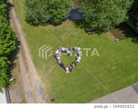 Wedding guests lined up in the shape of heart with bride and groom marriage people 104882612