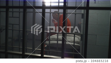 Elderly prisoner sits in prison cell in jail, eats food 104883218