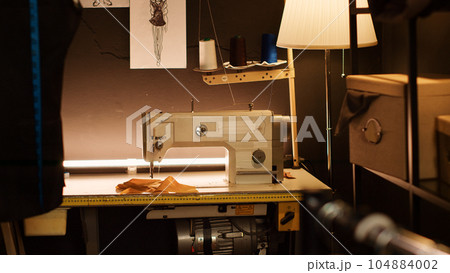 Tailor workshop sewing machine and tools used for custom made clothes and fashion collection, manufacturing industry. Industrial tailoring equipment at luxury atelier. Close up. Tailor workshop sewing machine and tools used for custom made clothes and fashion collection, manufacturing industry. Industrial tailoring equipment at luxury atelier. Close up. 104884002
