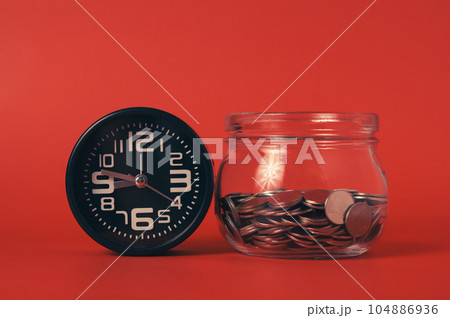 Money coins with alarm clock, Coins in glass jar on abstract background, Financial business investment, Growing money, Global financial crisis, People saving money, Money saving concept Money coins with alarm clock, Coins in glass jar on abstract background, Financial business investment, Growing money, Global financial crisis, People saving money, Money saving concept 104886936