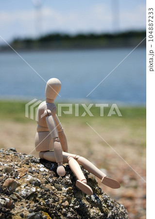 砂浜の岩に座るマネキン人形の様子 砂浜の岩に座るマネキン人形の様子 104887233