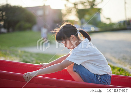 夏の夕方の住宅地の公園で遊んでいる小学生の女の子の様子 104887497