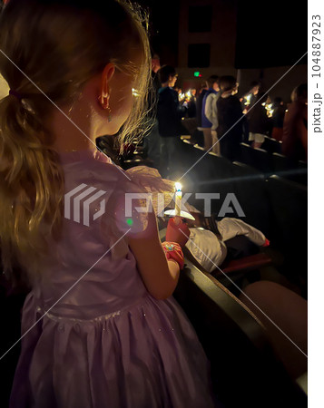 Caucasian girl in dress during a candle light church service.  104887923