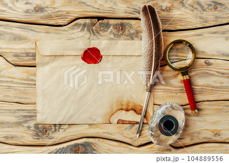 Old paper on brown wood background with feather 104889556