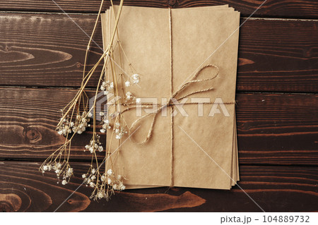 Blank sheet of paper with flower branch on wooden background 104889732