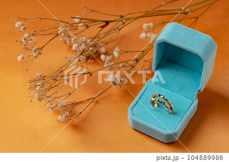 Golden ring in jewelry box on orange background Golden ring in jewelry box on orange background 104889986