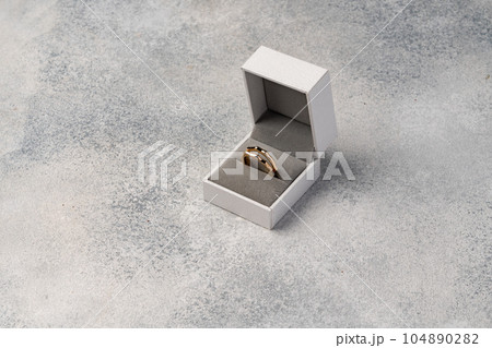 Golden ring in jewelry box on gray background Golden ring in jewelry box on gray background 104890282
