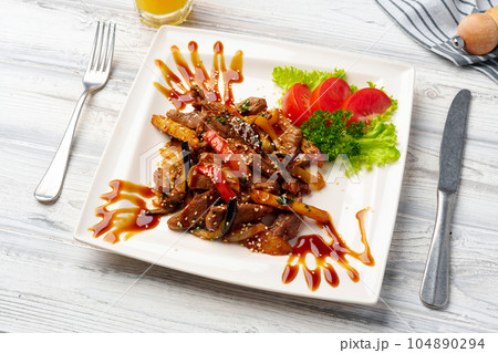 Beef and vegetables stir fry in a white plate on wooden table 104890294