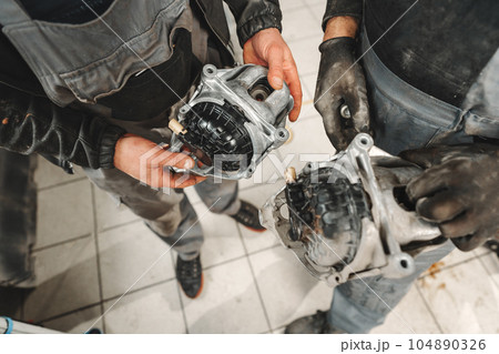 Young man mechanic repairing car parts on worktable in car service shop Young man mechanic repairing car parts on worktable in car service shop 104890326