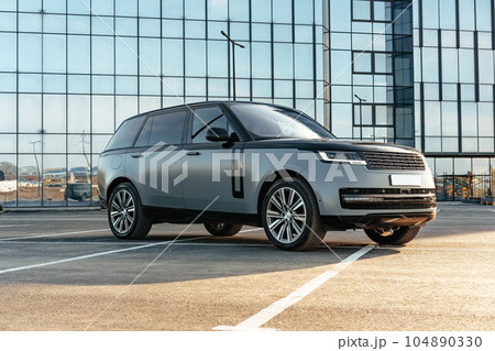 Luxury SUV car parked against a background of glass building Luxury SUV car parked against a background of glass building 104890330