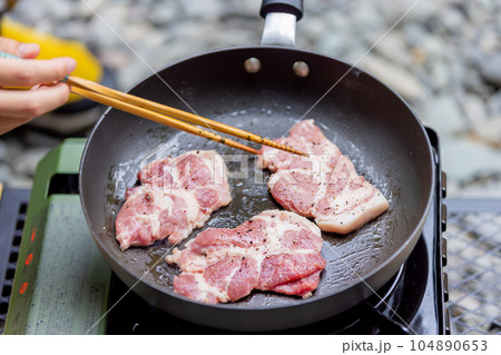 キャンプで豚肉を焼く男性 ガスコンロ キャンプで豚肉を焼く男性 ガスコンロ 104890653