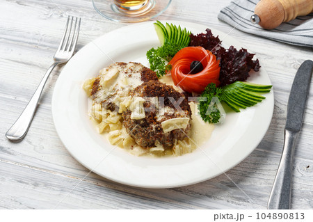 Two beef patties with sauce and fresh vegetables served on plate in cafe Two beef patties with sauce and fresh vegetables served on plate in cafe 104890813
