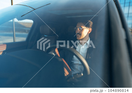 Young businessman in elegant suit driving luxury car Young businessman in elegant suit driving luxury car 104890814